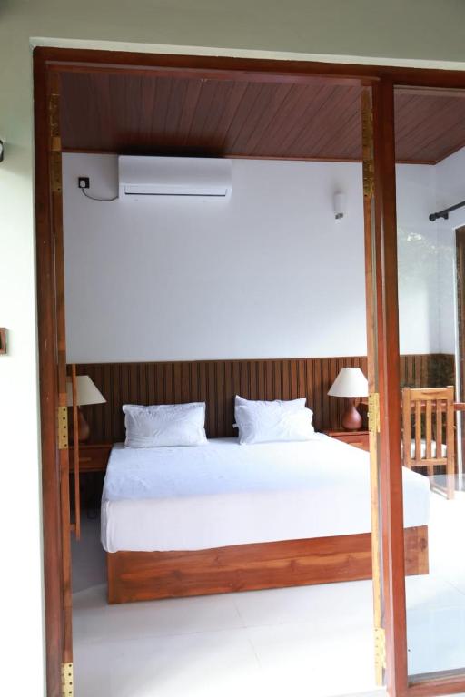 a bedroom with a large bed with white sheets at Visit Wilpattu in Pahala Maragahawewa