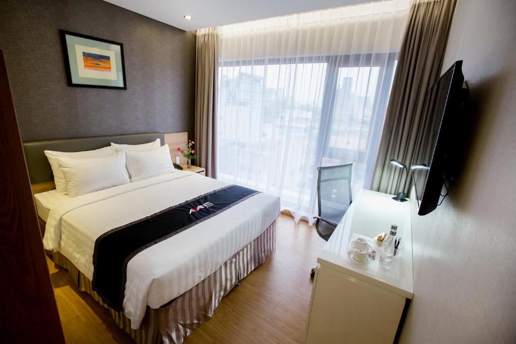 um quarto de hotel com uma cama e uma grande janela em Avanti Hotel em Ho Chi Minh