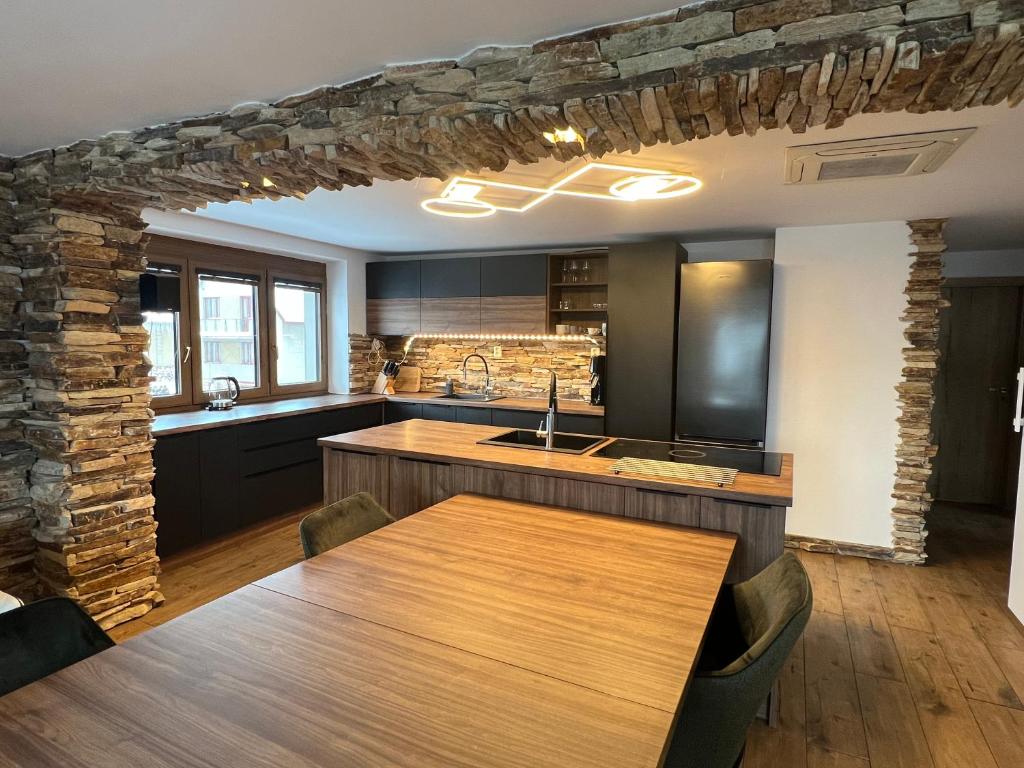 a kitchen with a wooden table and a stone wall at Apartmán Horal in Jilemnice