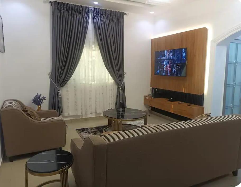 a living room with a couch and a tv at Travel Lodge Apartment in Sagisa