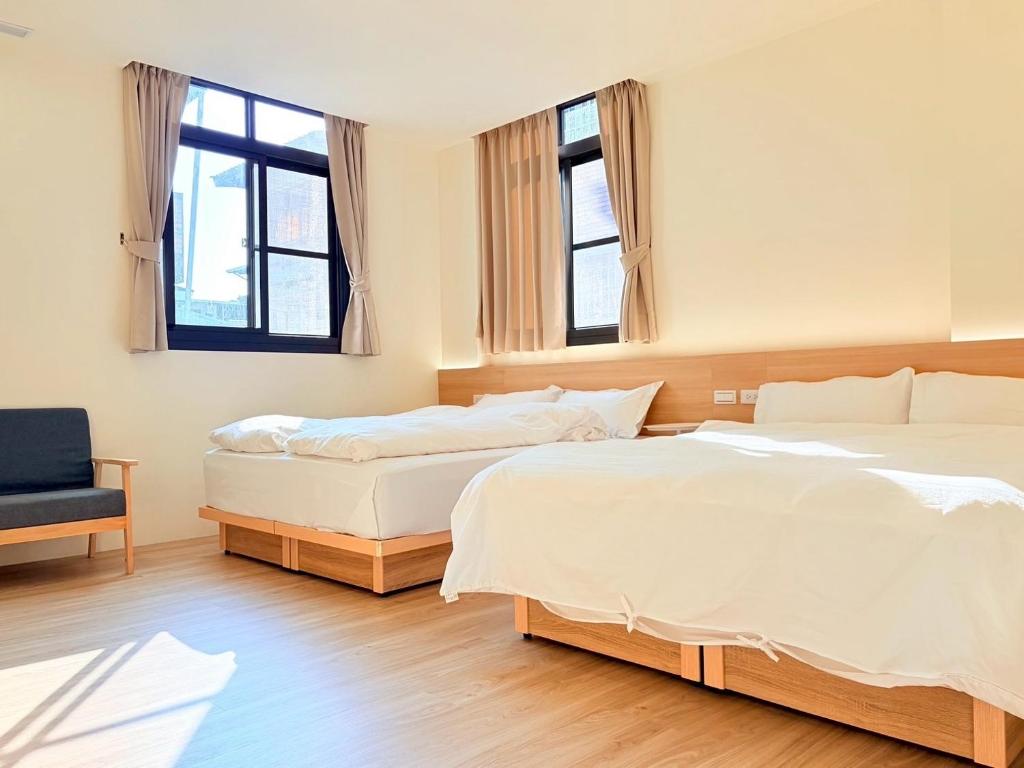 twee bedden in een slaapkamer met twee ramen bij Jian Guo Hotel in Pingtung City