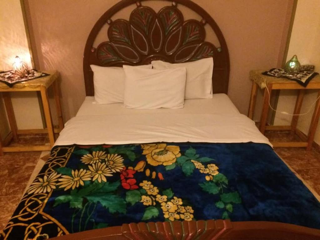 a bedroom with a bed with a floral bedspread at Sphinx in Al Karnak