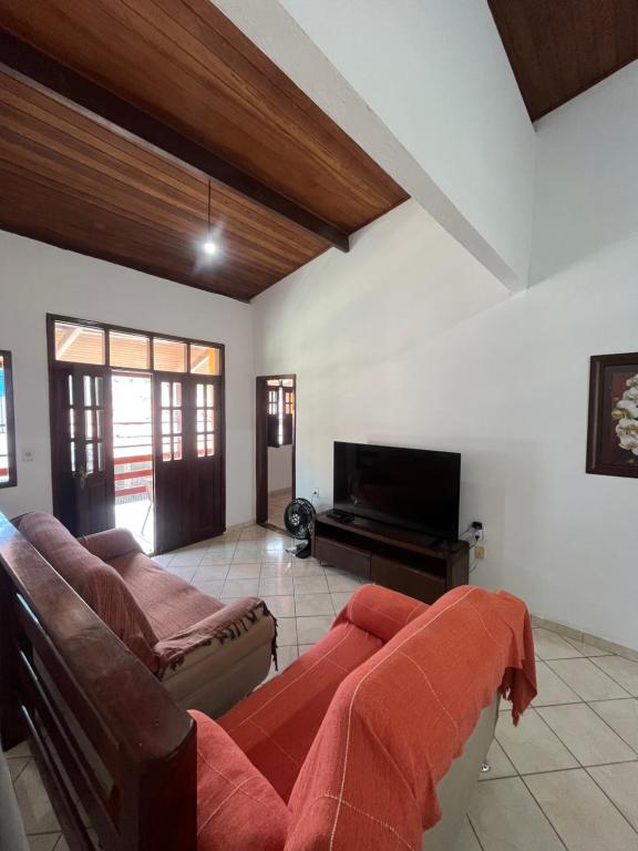 a living room with a couch and a flat screen tv at Casa Fácil in Itacaré