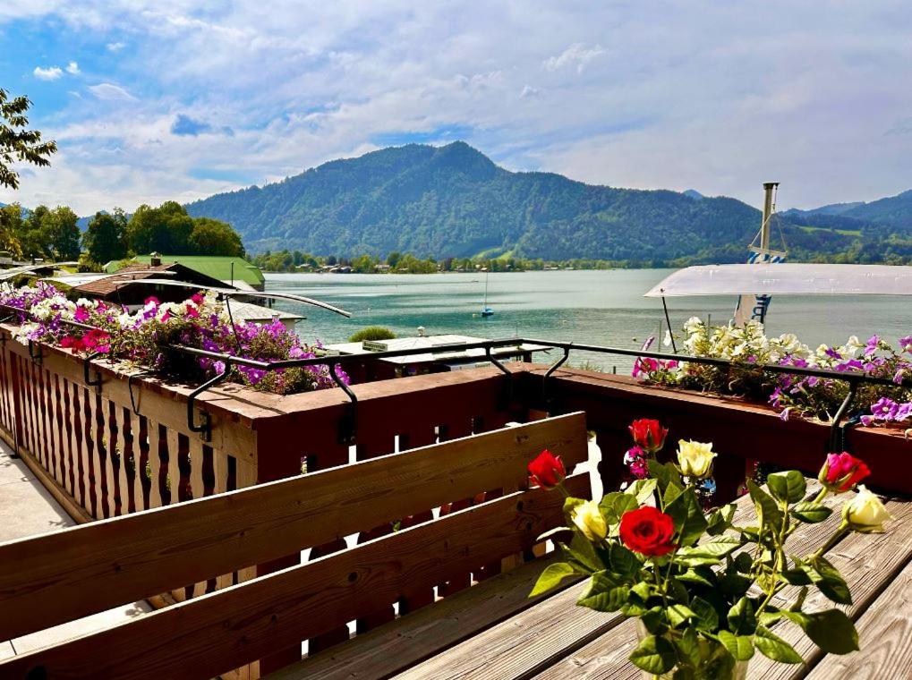 a bunch of flowers on a deck with a view of the water at Hotel Fischerstüberl am See in Tegernsee