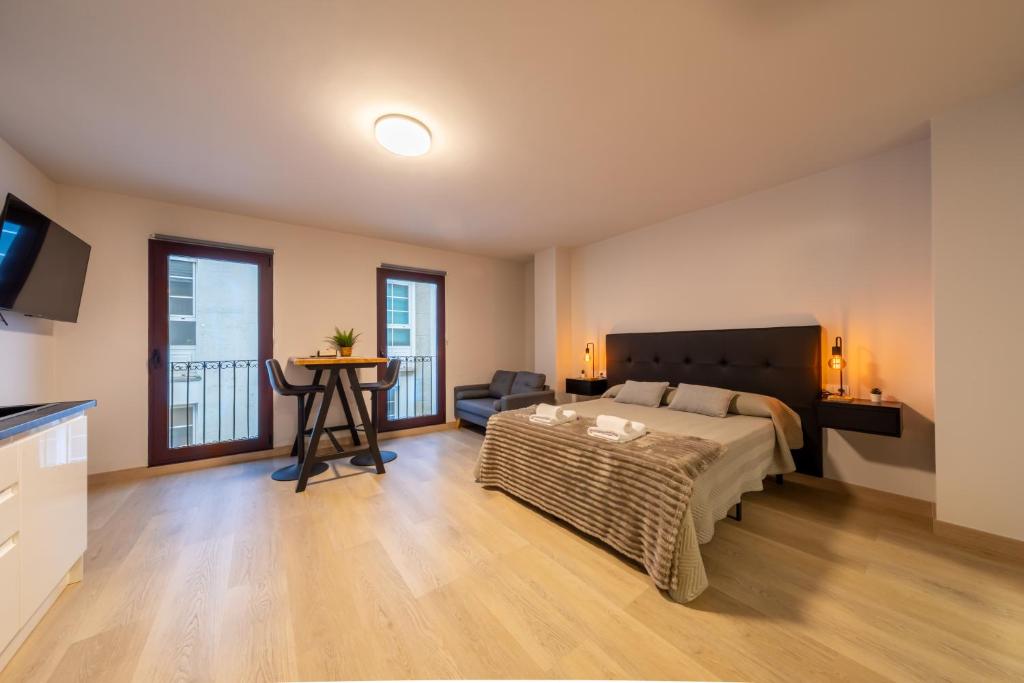 een slaapkamer met een bed, een bank en een tafel bij Apartamentos muralla de Lugo in Lugo