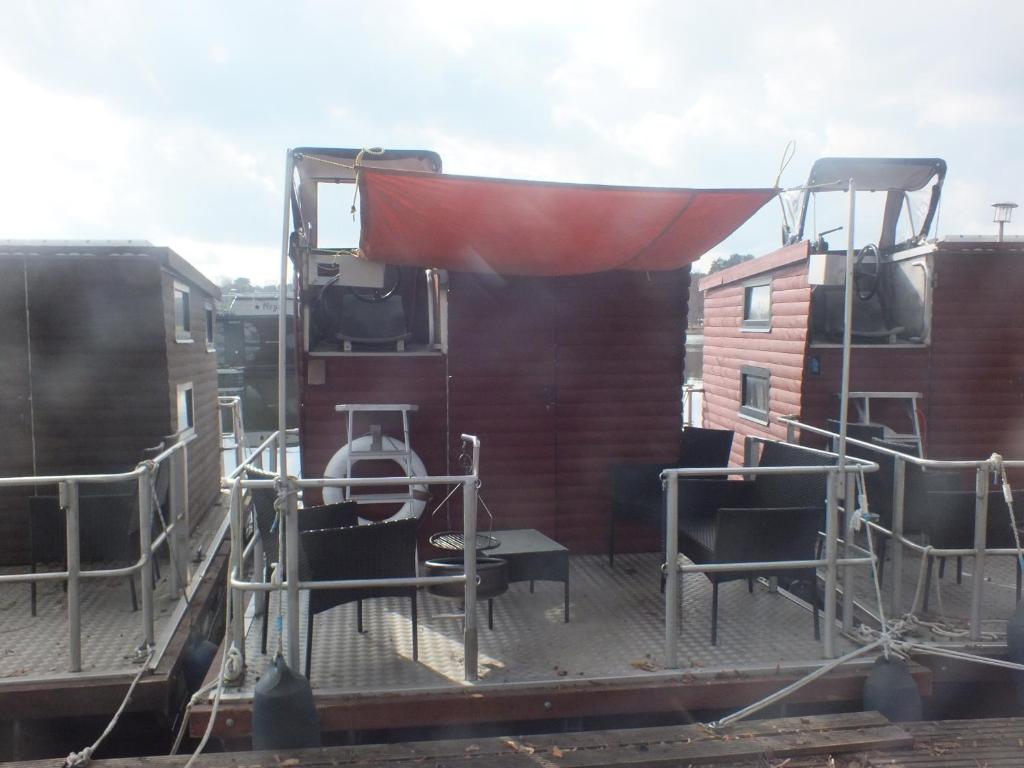a deck with chairs and a red covering on a train at Kleines Hausboot - ideal für Ihren Angelurlaub! in Lychen