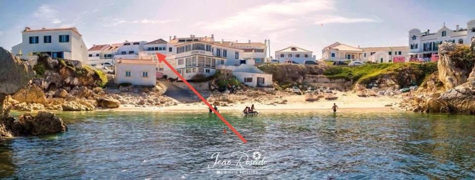 a person in the water near a beach with houses at Baleal Bali Casa da Ilha in Baleal