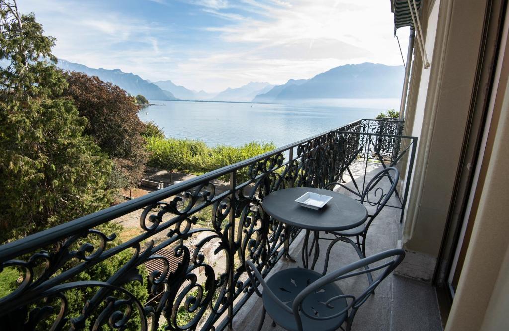 a balcony with a table and chairs and a view of the water at La Résidence des Trois Couronnes in Vevey
