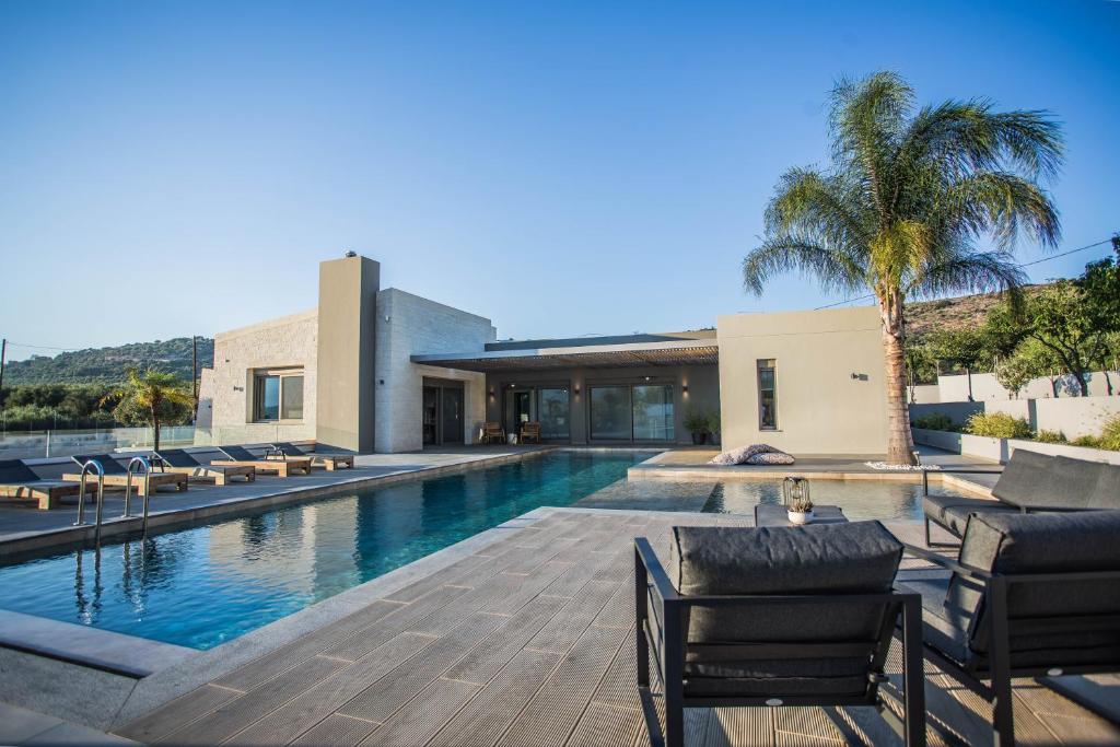 a swimming pool with chairs next to a building at Villa Aori in Kariá