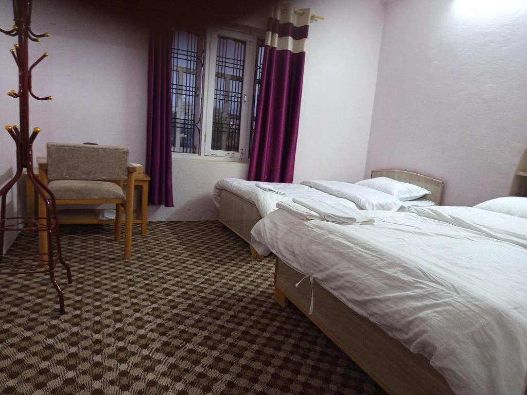 una stanza d'albergo con due letti e una sedia di Annapurna Himdrishya Pokhara a Pokhara