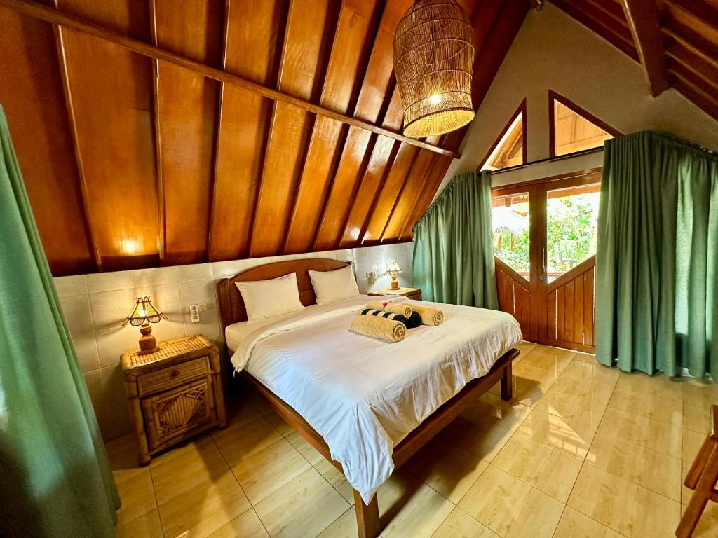 een slaapkamer met een bed met een houten plafond bij Sunny Rose Bungalows Gili Air - Adults Only in Gili Air