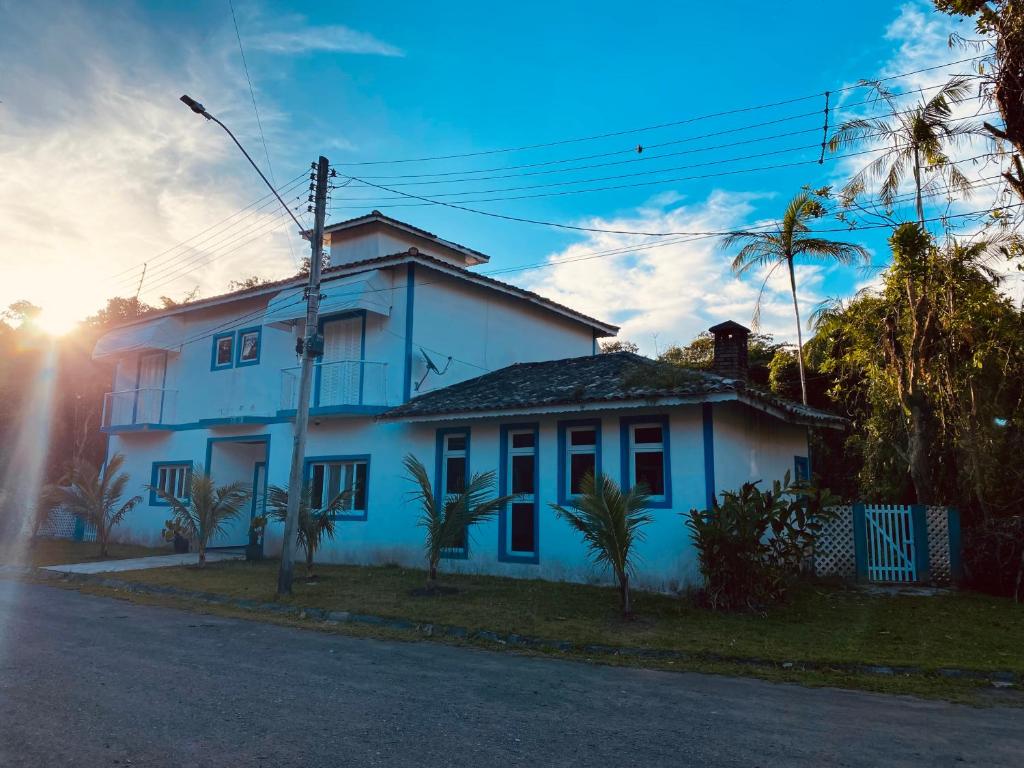 a white house with palm trees in front of it at Casa Verão Guaratuba - Bertioga in Bertioga
