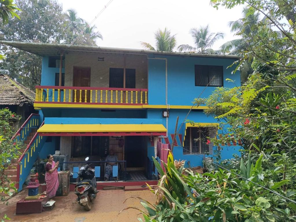 a blue house with people standing outside of it at Sheshatara Homestay in Honāvar