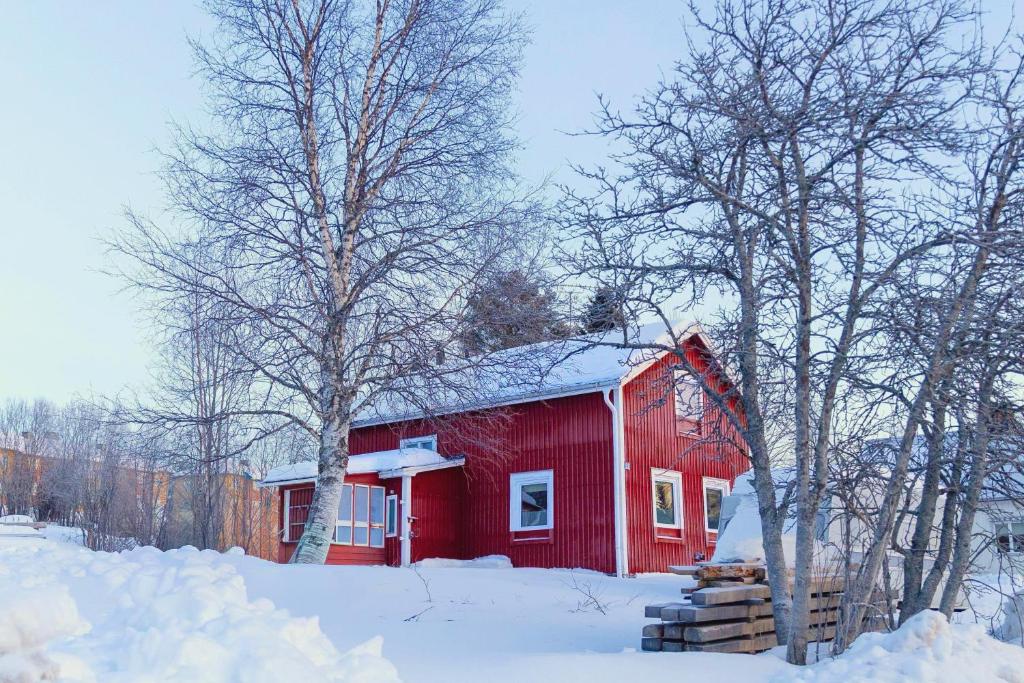 un fienile rosso con la neve sul tetto di Gemütliche Ferienwohnung in Nordschweden a Glommersträsk