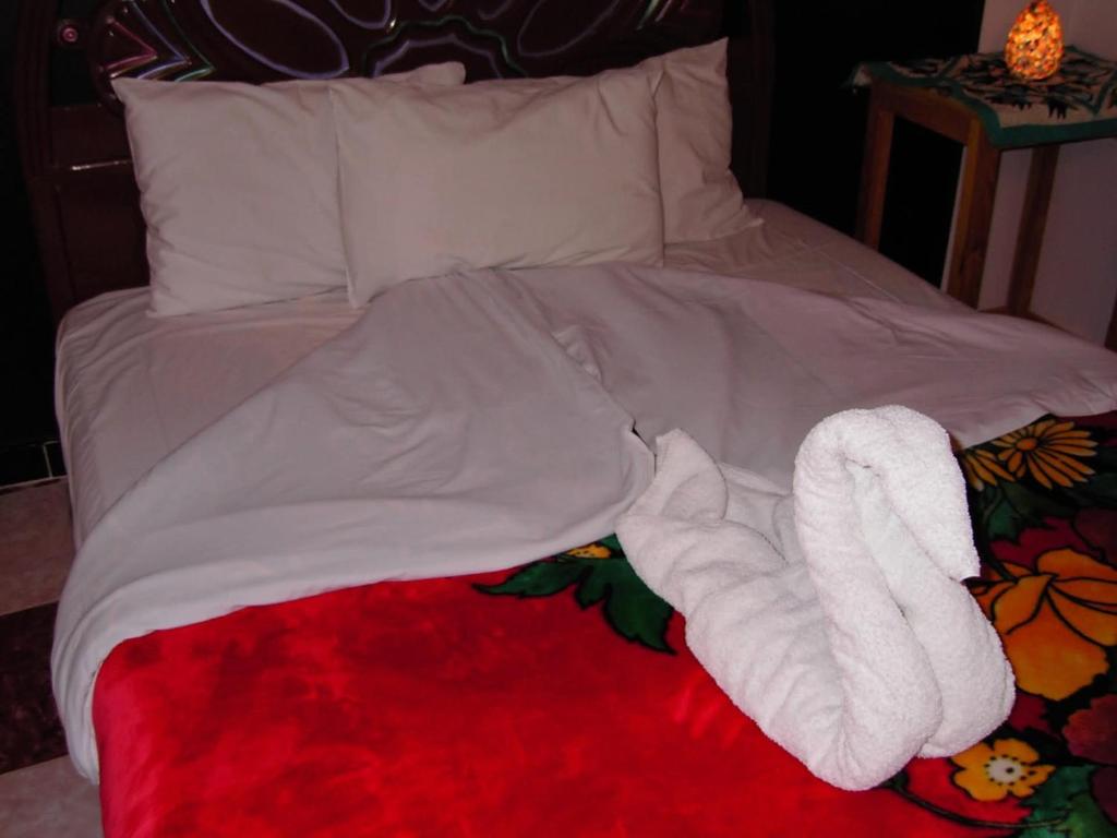 a bed with a white towel animal laying on it at Sphinx in Al Karnak