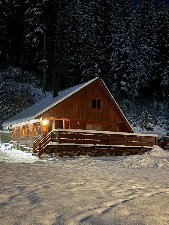 a large wooden barn with a light on it in the snow at Areál Lesková in Velké Karlovice