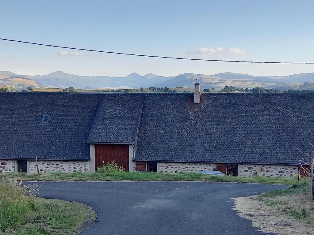 a building with a black roof and a road at Chambres d'hôtes du Chênelong Cantal in Marchastel
