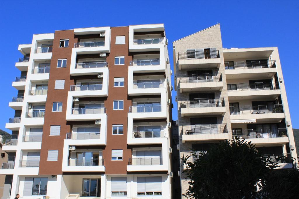 Centar New Loki Apartments في بودفا: عمارة سكنية طويلة لونها ابيض وبني