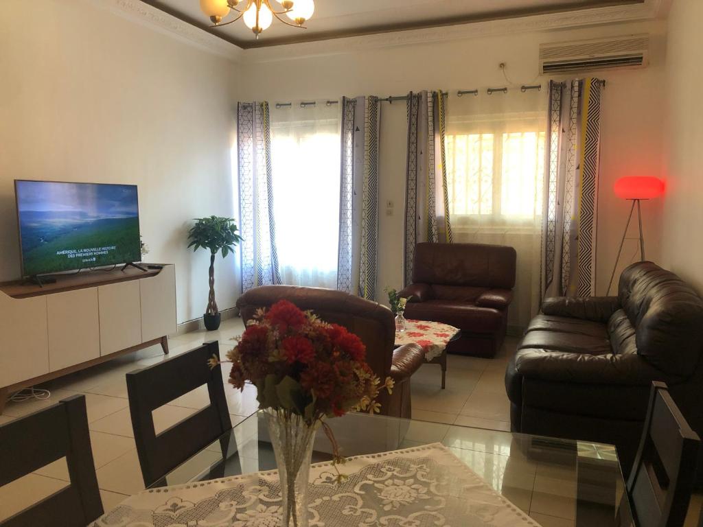 un soggiorno con divani, TV e tavolo di Grand Appart ESSOS camp sonel a Yaoundé