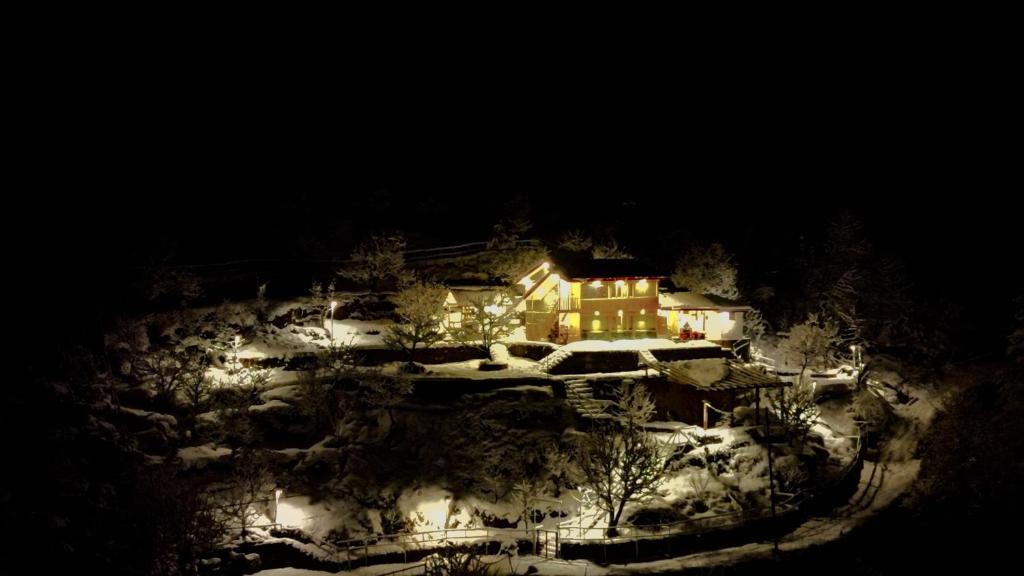 a house on a snow covered hill at night at The Himalayan Home in Nagar