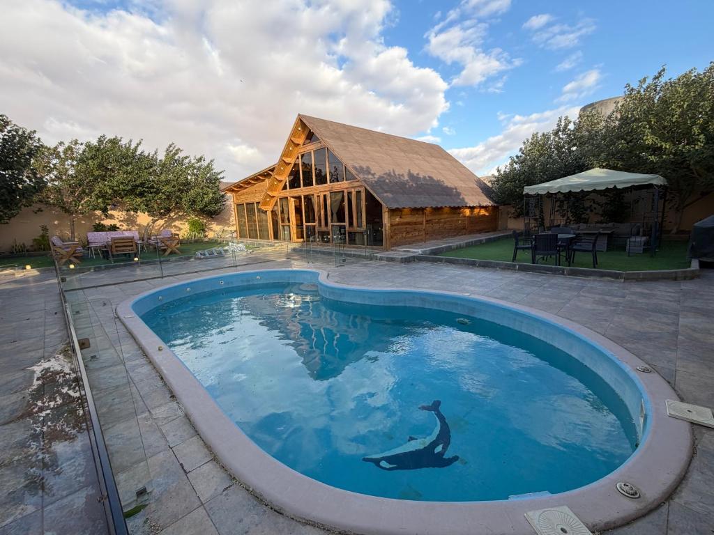 a swimming pool with a dolphin in front of a house at أكواخ كيفاء الريفية in Tabuk