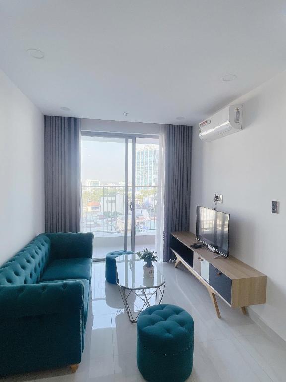 a living room with a couch and a tv at Happy One Central Hottel in Trạm Chánh An