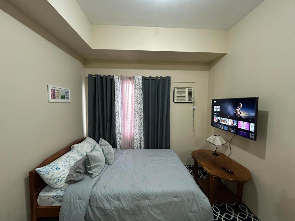 a bedroom with a bed and a flat screen tv at Avida Tower 1, Unit 2003 - Chi's Place in Cagayan de Oro