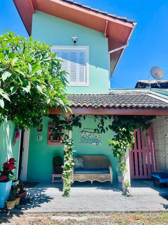 a green house with a bench in front of it at Casa Verde Bertioga, um espaço cheio de charme com três praias - Indaiá, Pedra Selada e Riviera de São Lourenço para visitar a pé! in Bertioga