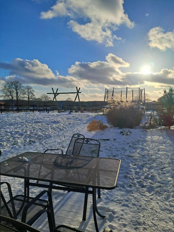 un tavolo e delle sedie in un campo innevato con una panchina di B&B V.K. PGmbH a Saint-Vith