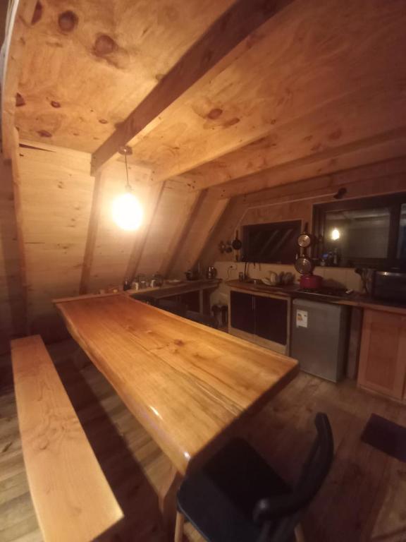 a large wooden counter in a kitchen with a table at Cabañas bosque sur in Curarrehue