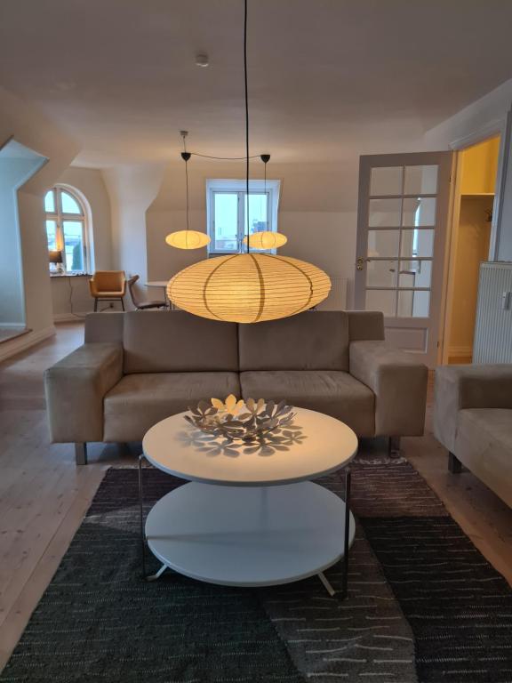 a living room with a couch and a table at Exclusive boende Suite 2 med 4 bäddar i stort sovrum varav 2 bäddar kan stänga om sig in Frederikshavn