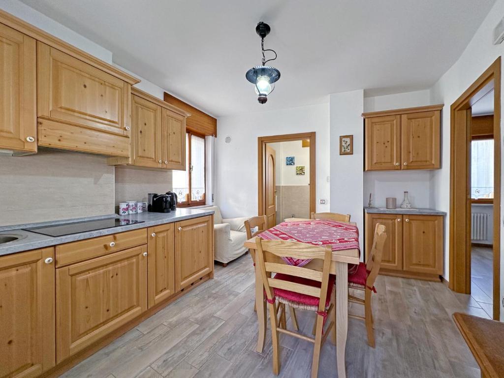a kitchen with wooden cabinets and a table with chairs at BBkey La cjase SOT LA STRETE in Arta Terme