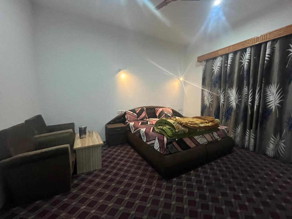 a room with a bed and a couch and a chair at Hotel Apex in Srinagar