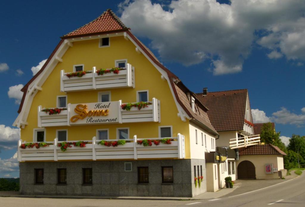 ein großes gelbes Gebäude mit weißen Balkonen und Blumen in der Unterkunft Hotel & Restaurant Sonne in Rudersberg