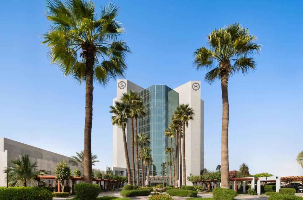 a building with palm trees in front of it at Sheraton Jeddah Hotel in Jeddah