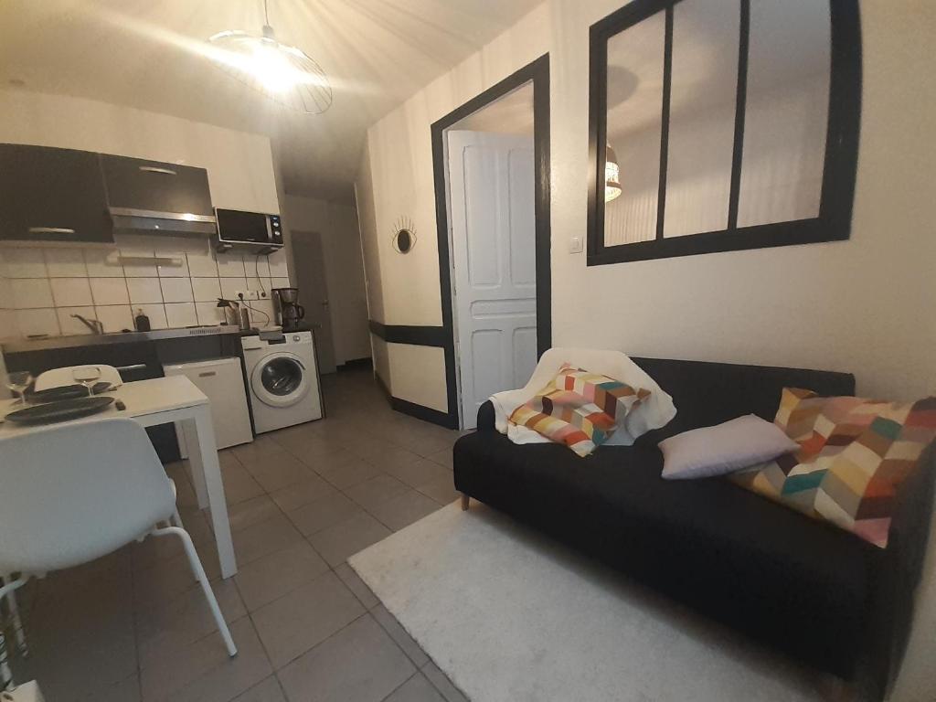 a living room with a black couch and a kitchen at Elise en plein coeur de la ville in Saint-Étienne