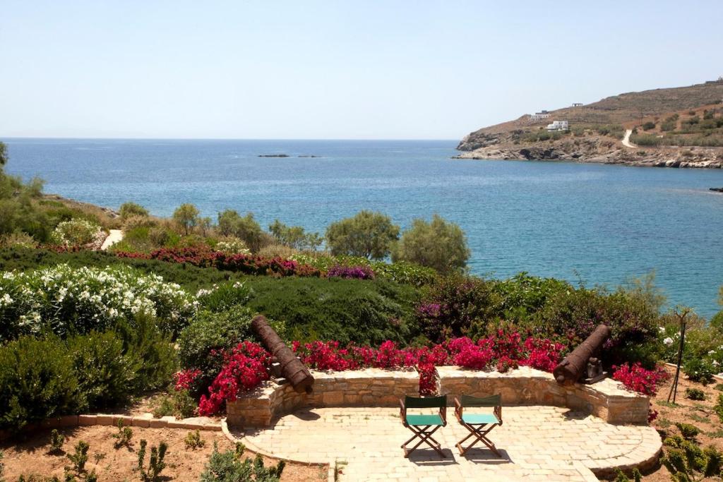 two chairs in a garden with a view of the water at Beachfront Majestic Villa in Liaropá