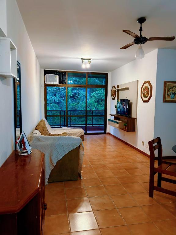 a living room with a couch and a large window at Exelente Localiazação - 50m Enseada e Pitangueiras - Apt Saint Patrick in Guarujá