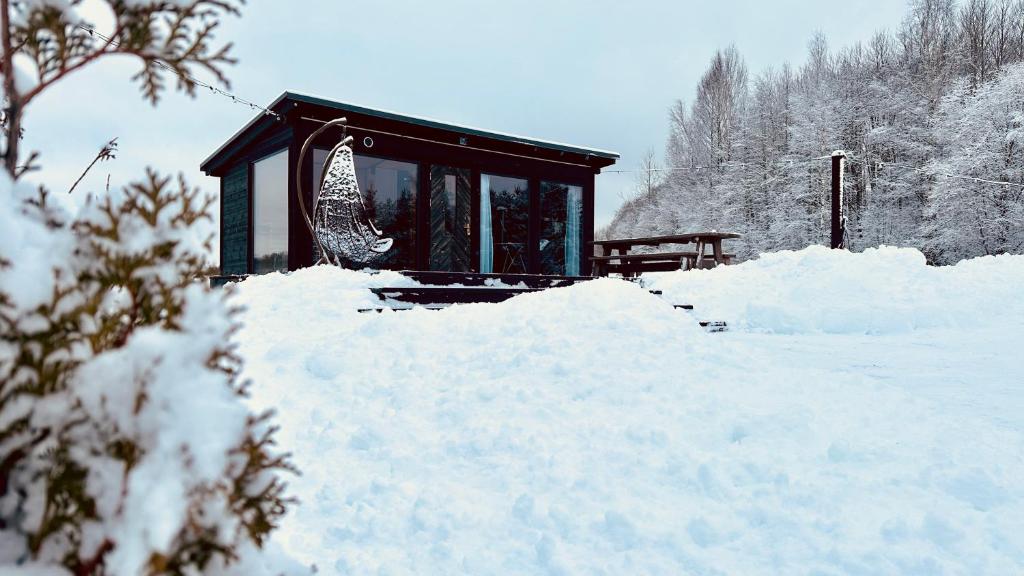 a small building covered in snow next to a pile of snow at Melnā kalna kamene, sauna iekļauta cenā in Vestiena