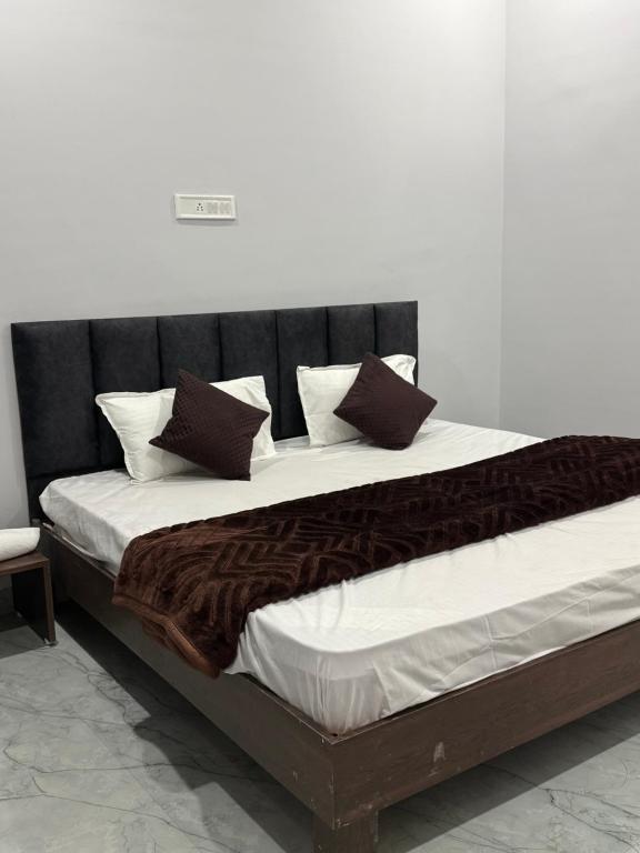 a large bed with brown and white pillows on it at Hotel Sarkar in Indore