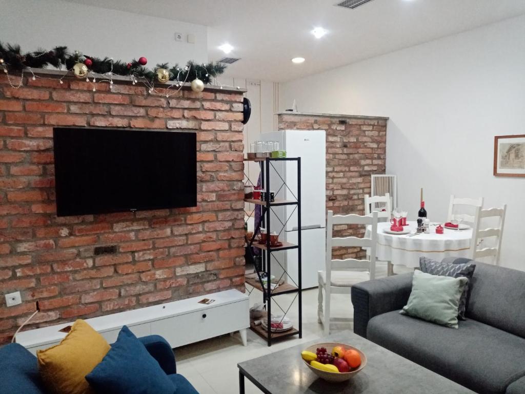 een woonkamer met een bakstenen muur en een flatscreen-tv bij Sava & Double Rooms in Prijedor