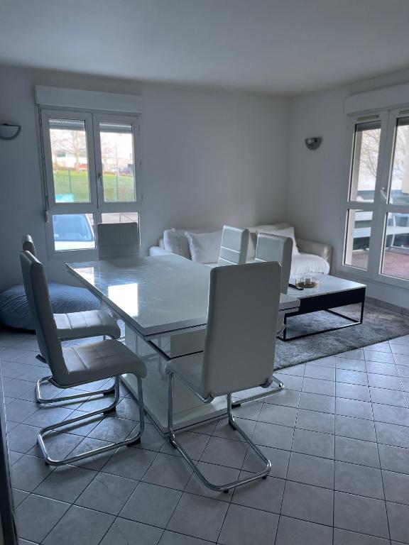 a dining table and chairs in a living room at Appartement 6 personnes avec jacuzzi in Torcy