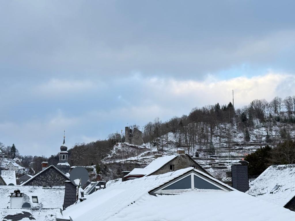 a snow covered town with houses and a mountain at Hotel Alt Montjoie in Monschau