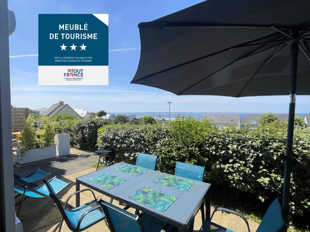 un tavolo e sedie con un ombrellone in un patio di Les terrasses de Pentrez - 11 a Saint-Nic