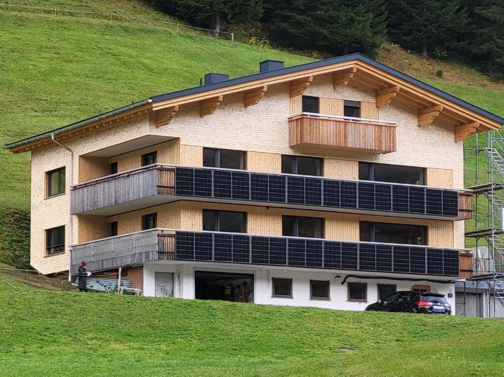 a building with solar panels on the side of a hill at Gästehaus Bischof in Damuls