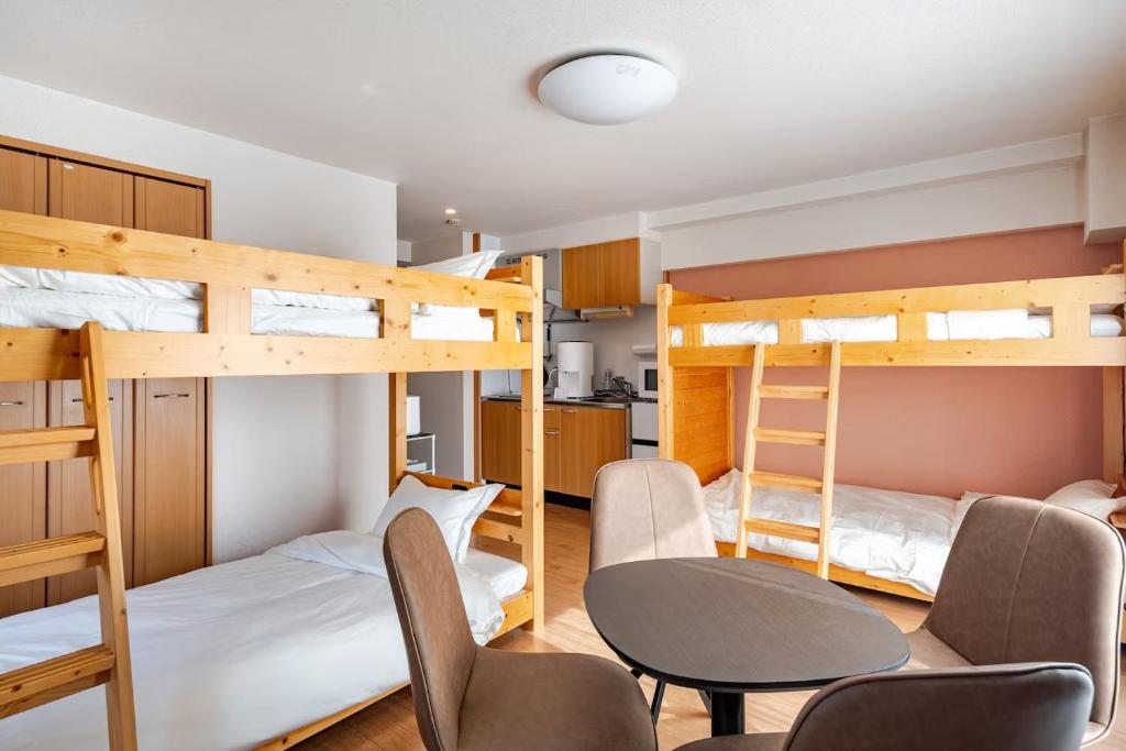 a room with two bunk beds and a table and chairs at ライズ201 in Kasugai