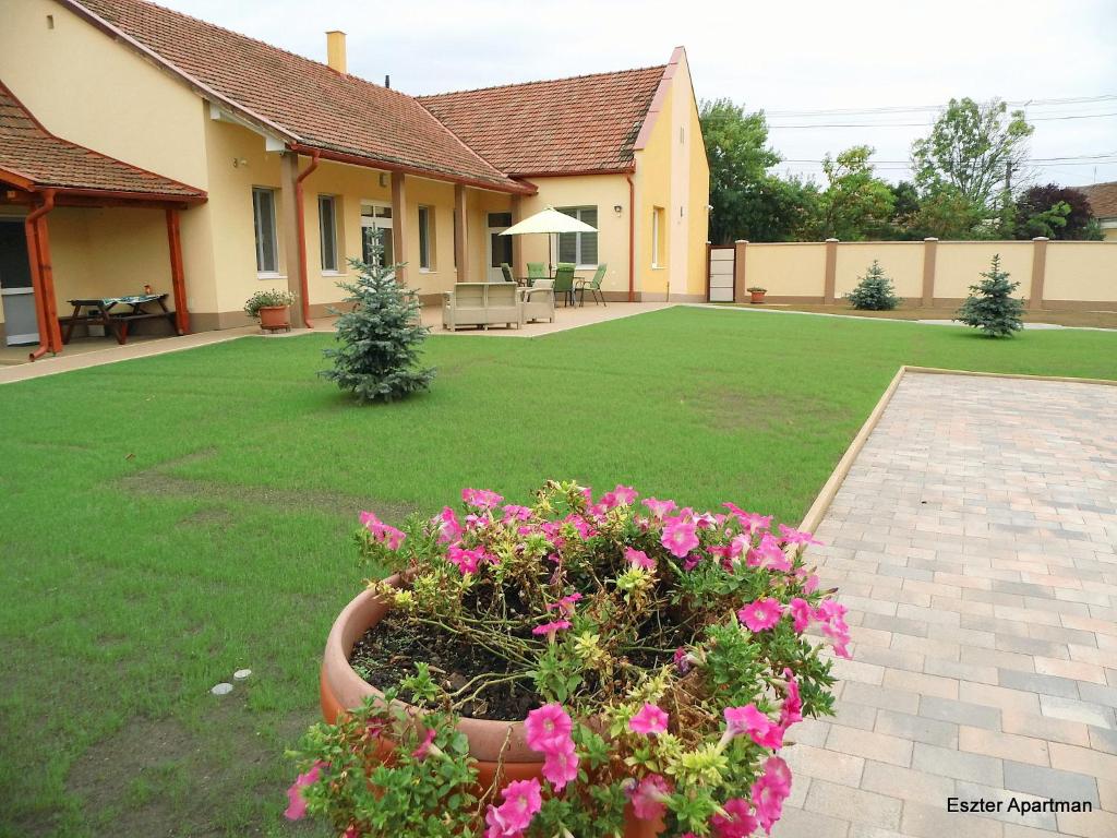 a house with a yard with pink flowers in the yard at Eszter Apartman in Békéscsaba