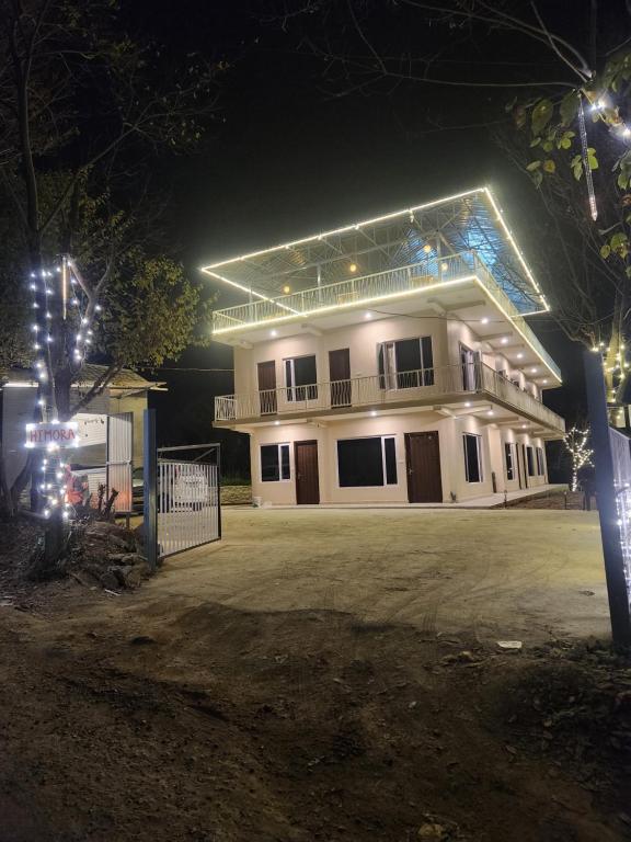 a large white building with lights on it at night at Himora Bir in Bīr