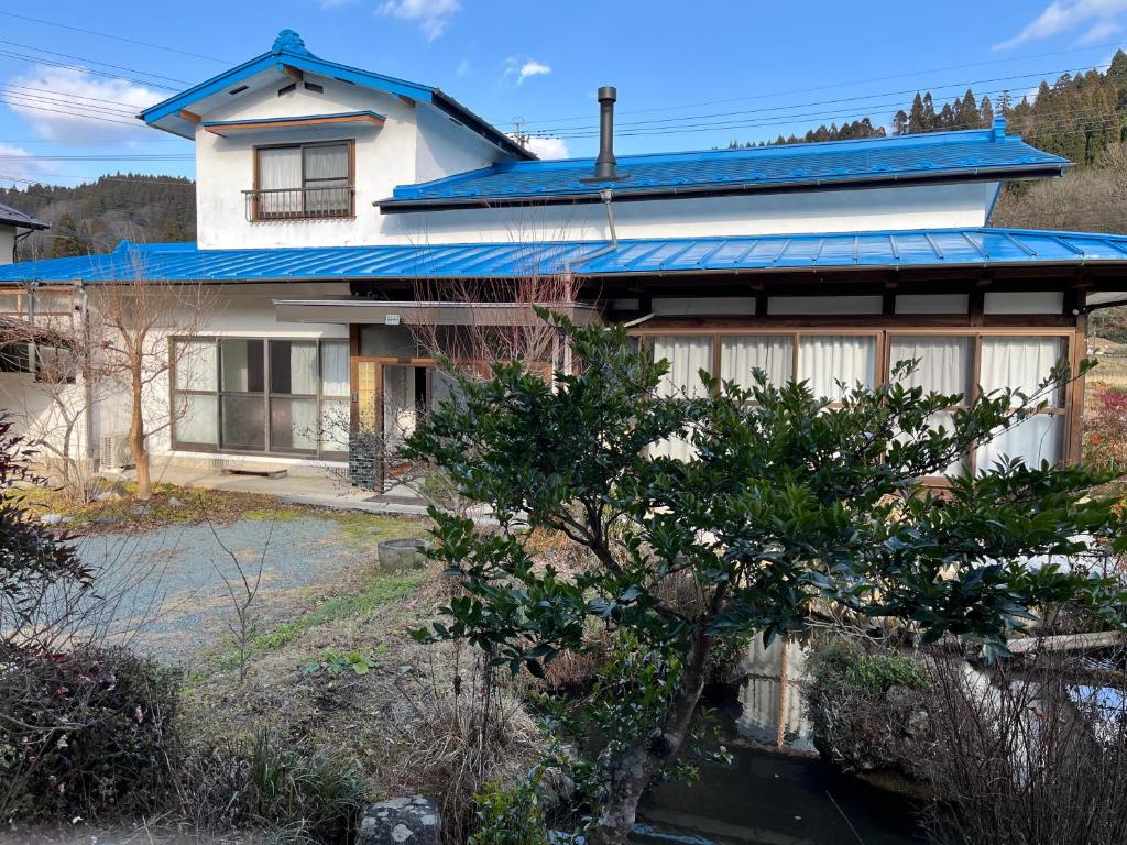 ein Haus mit einem blauen Blechdach in der Unterkunft Kamida179 in Oguni