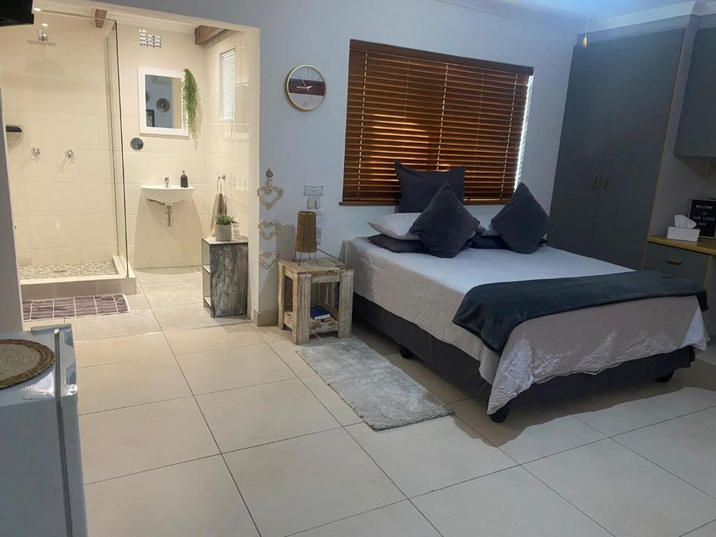 a bedroom with a bed and a bathroom with a shower at The Little Gem in Clanwilliam